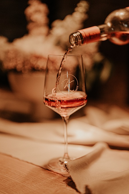 Glänzendes Weinglas auf einer Tischdecke in das Roséwein eingeschenkt wird