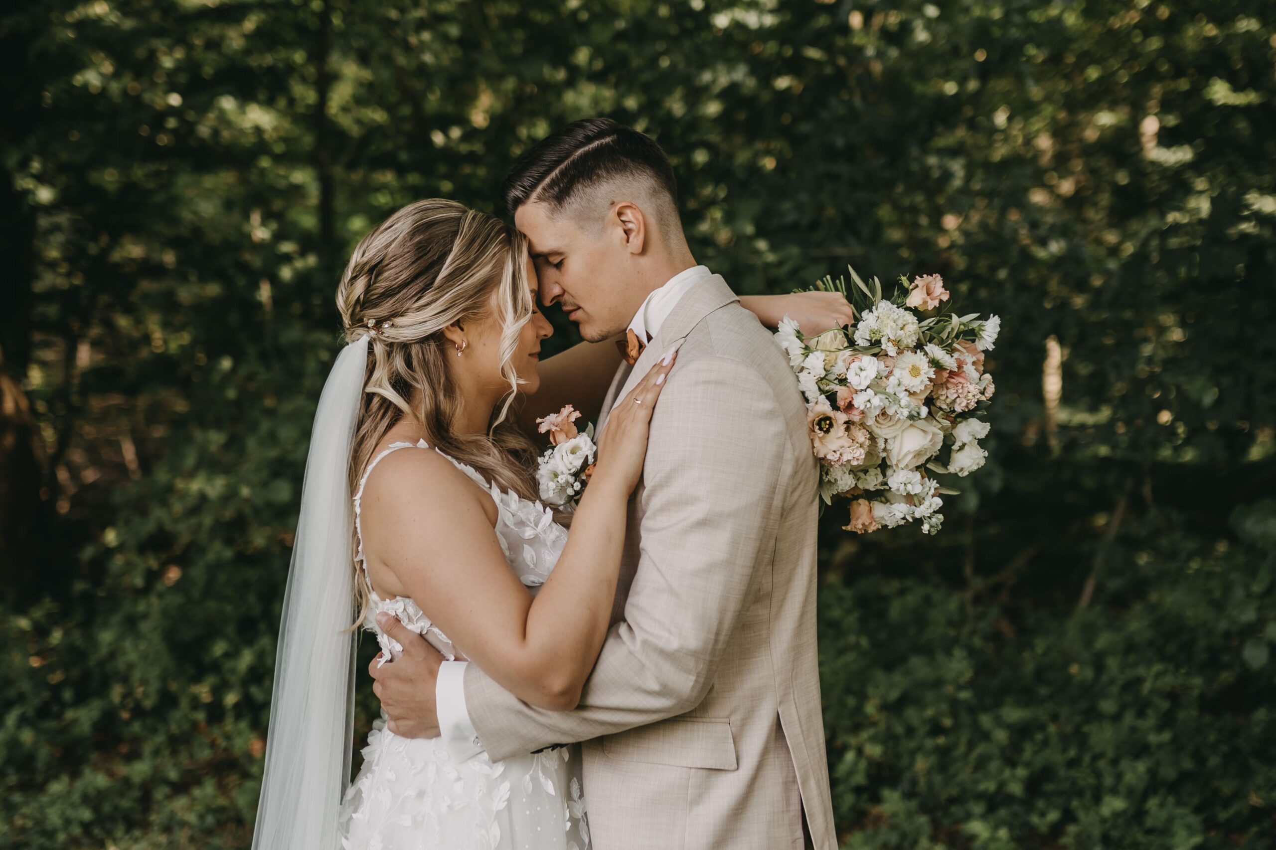 Das Brautpaar vor einem Wald umarmt sich liebevoll