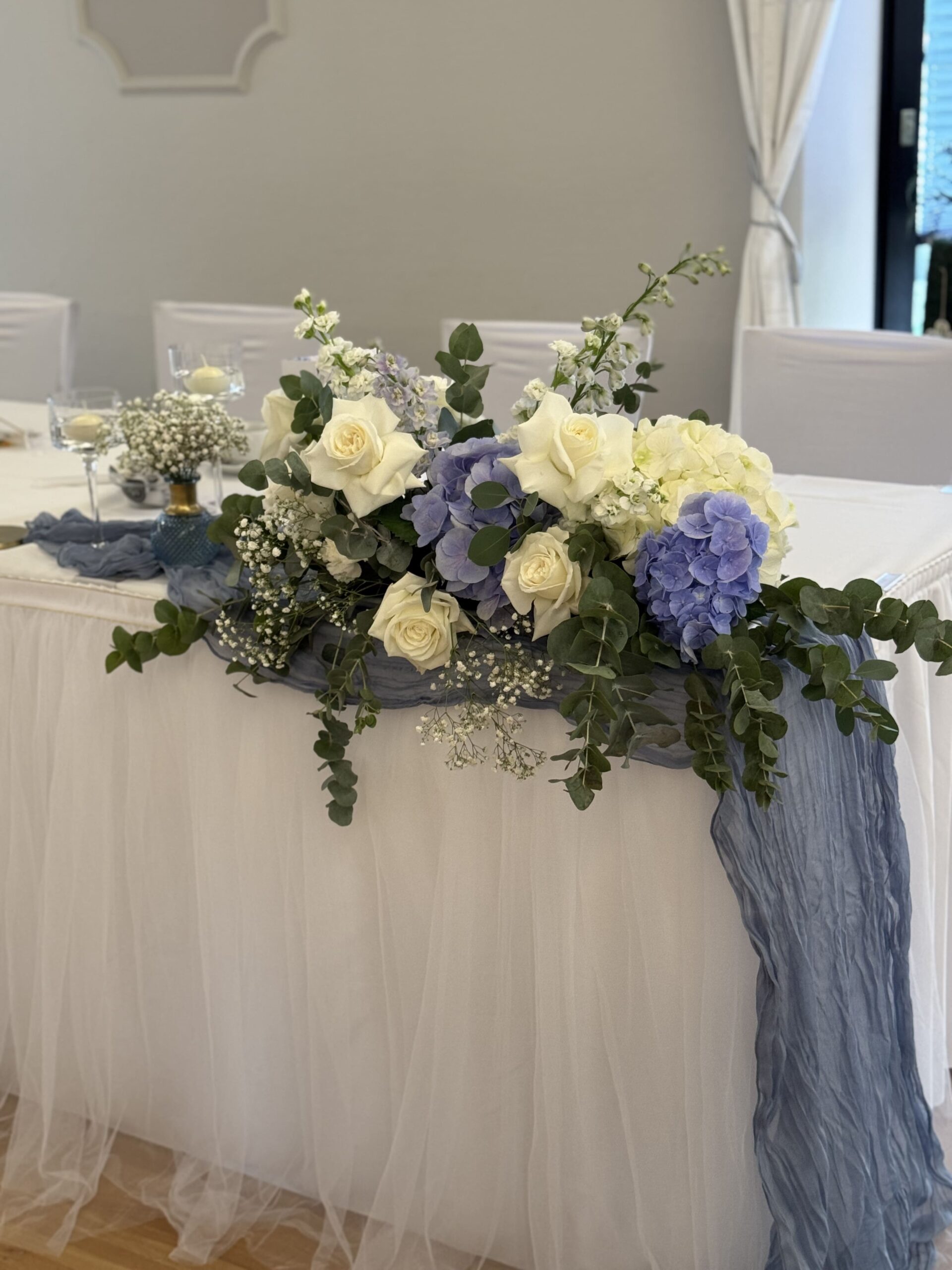 Ein großer Blumenblock auf dem Tisch des Brautpaares in weiß und blau
