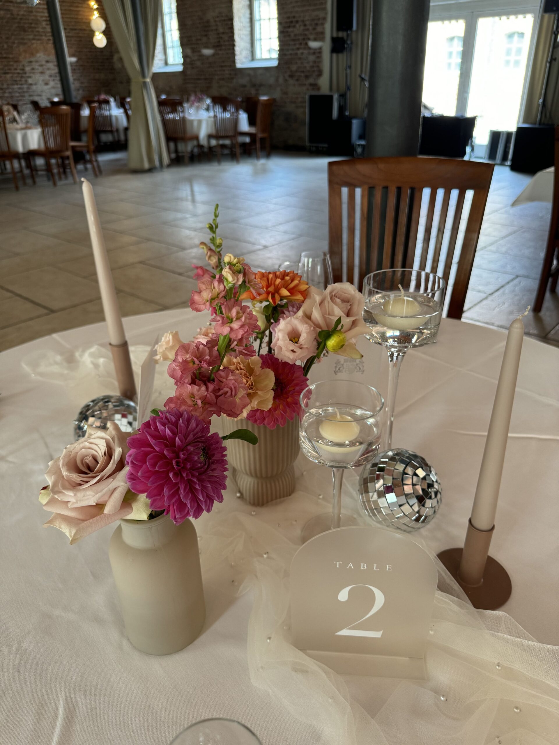 Ein gedeckter Tisch für Hochzeitsgäste mit Tischnummer und kleinen Discokugeln