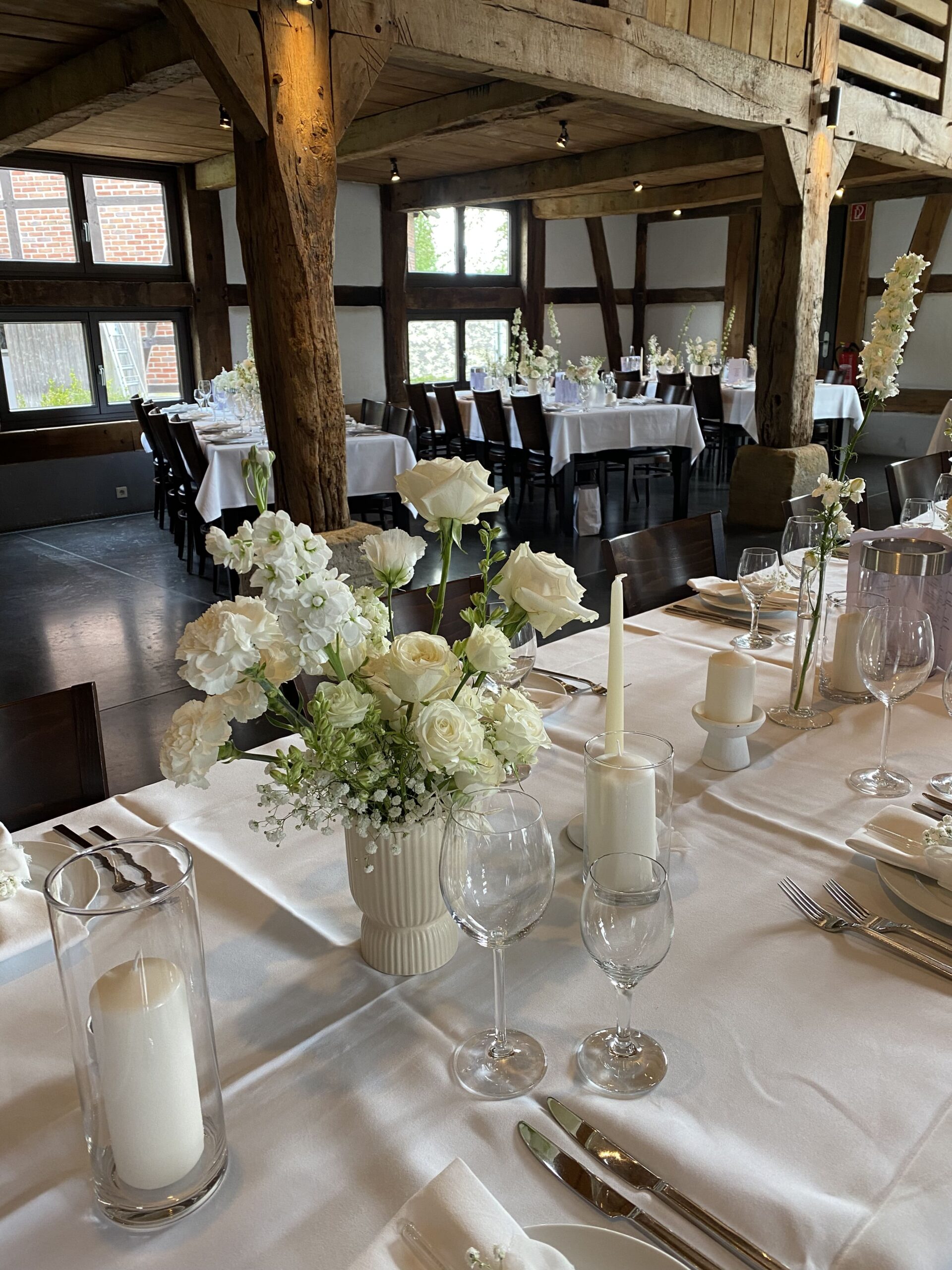 Weiße Blumen auf einem langen Gästetisch in einer weißen Vase