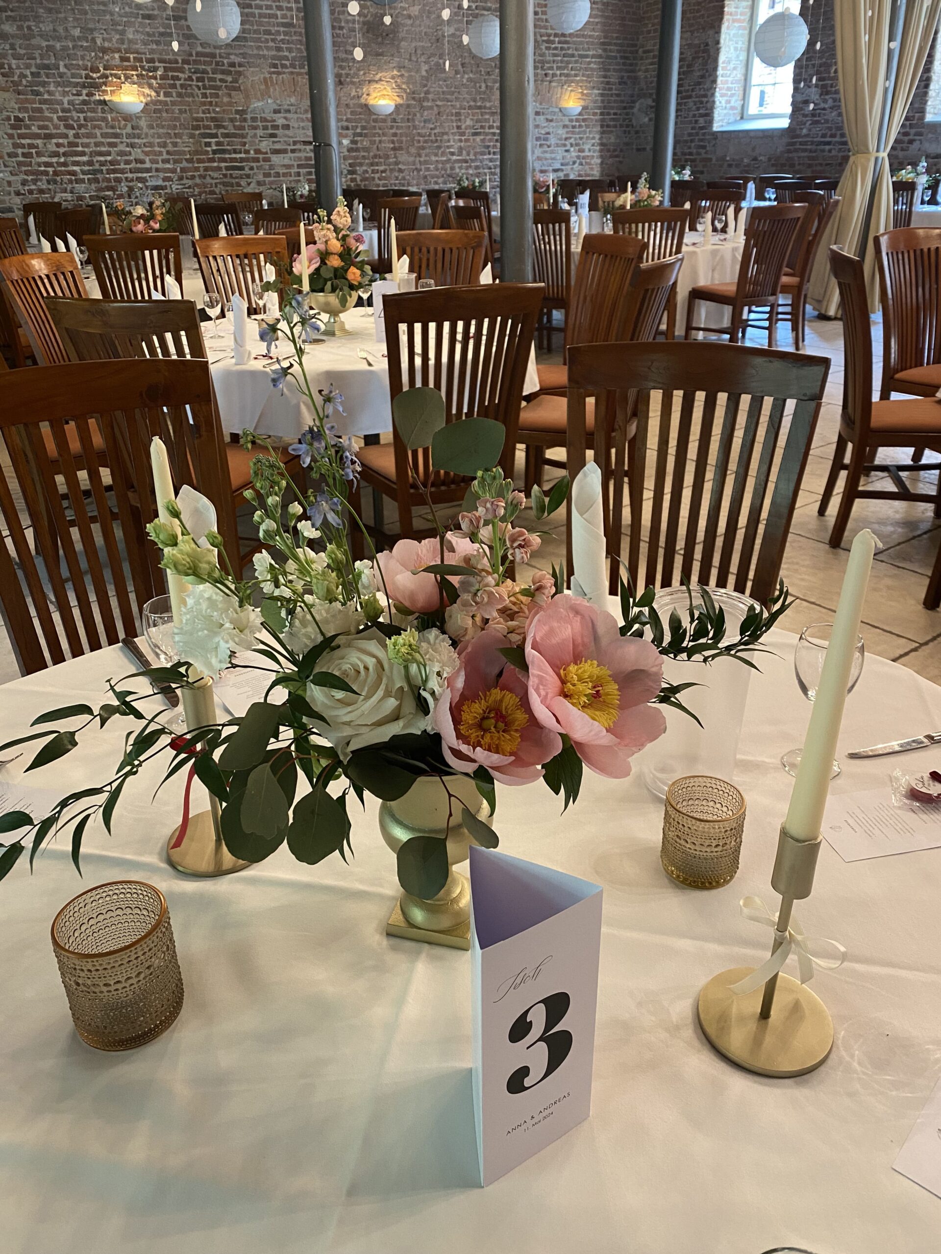 Ein Blumenstrauß auf einem gedeckten Tisch mit einer Tischnummer für die Gäste